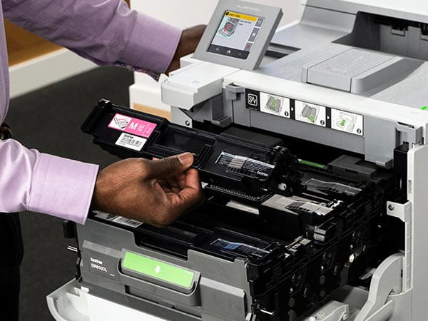 Man installing new magenta toner cartridge in printer