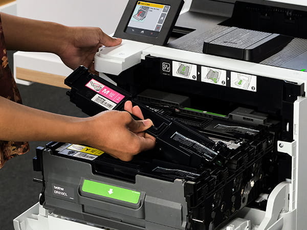 Woman installing new magenta toner cartridge in printer