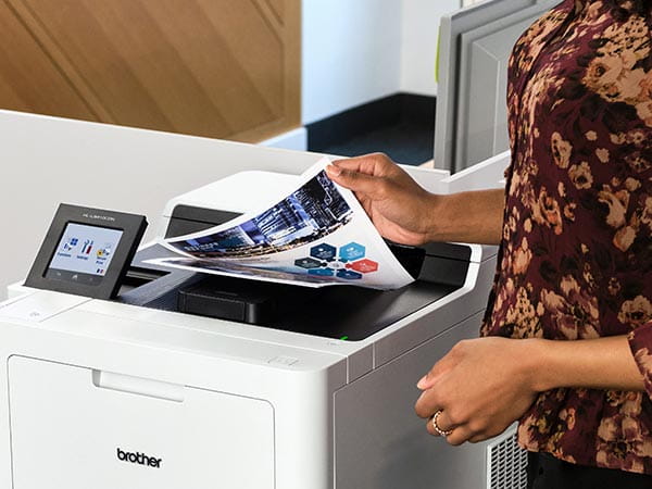 Woman removing multipage color business report from printer's output tray