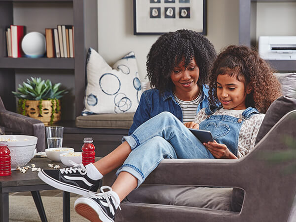 Mother and daughter in living room, printing schoolwork from a mobile tablet