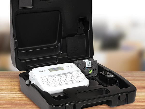 Label maker, 2 label tape cartridges, and AC adapter in carrying case on office desk