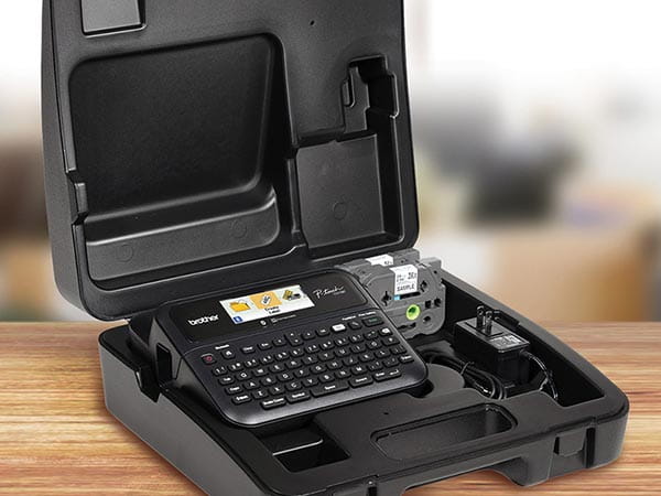 Label maker, 2 label tape cartridges, and AC adapter in carrying case on office desk