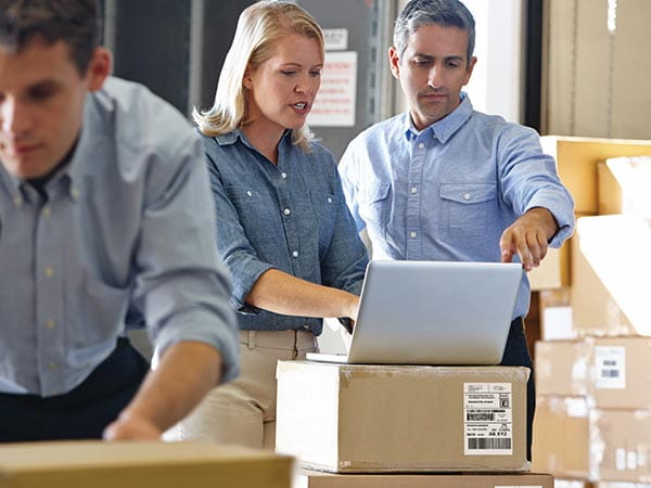 People in warehouse using software on PC to create address labels