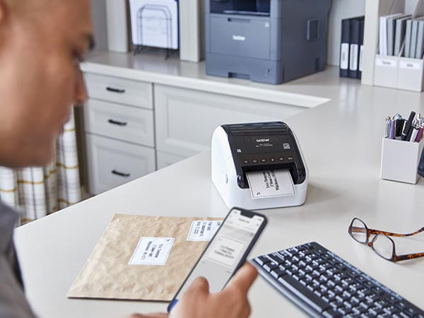 Man in home office printing address label from mobile phone