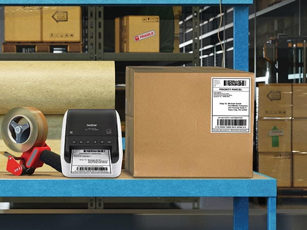 Label printer on warehouse table, printing USPS shipping label