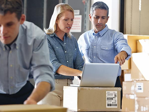 People in warehouse using software on PC to create shipping labels