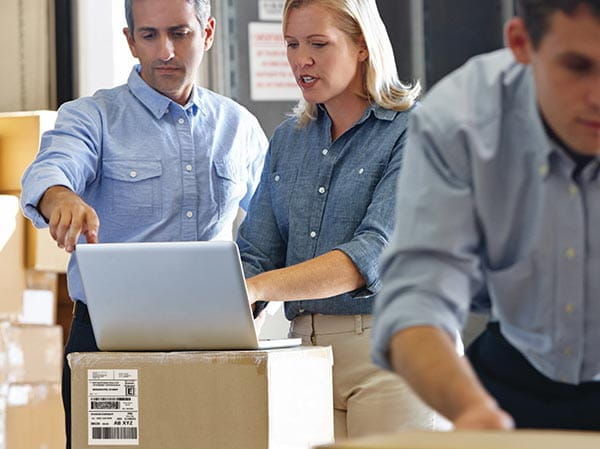 People in warehouse using software on PC to create shipping labels