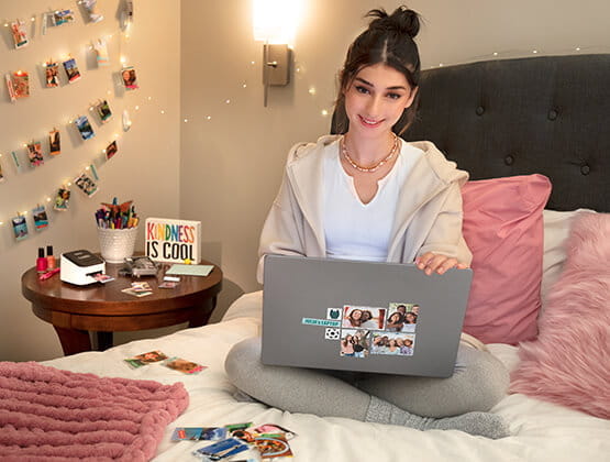 Teen girl sittin on bed in room with ColAura printer on side table.