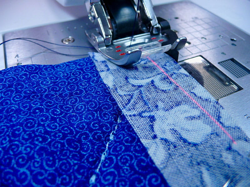 the fabric under the sewing machine displaying the machines laser while sewing