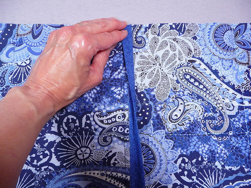 2 pieces of fabric sewed together on the corner with a corner piece, hand holding it to display the stiching
