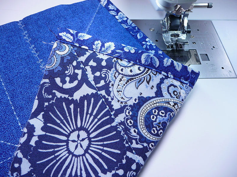Sewn fabric on the machine folded on the corner to display the stiching on the edges