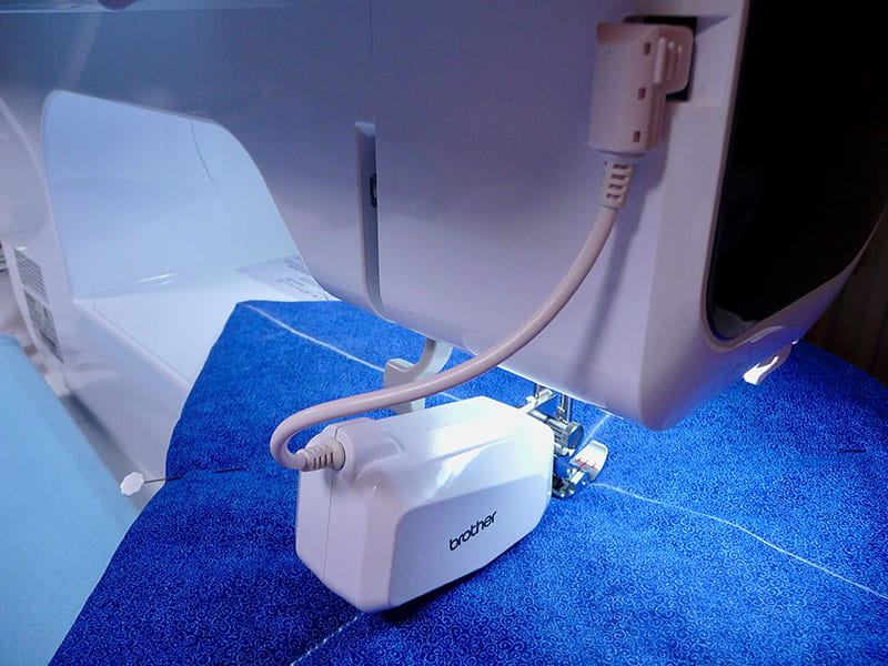 Brother sewing machine sewing the bright blue fabric