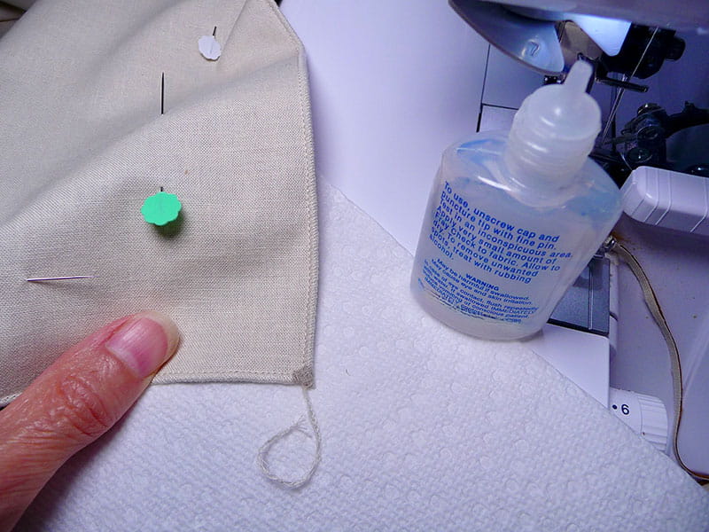Napkin with pin in it next to open fabric glue