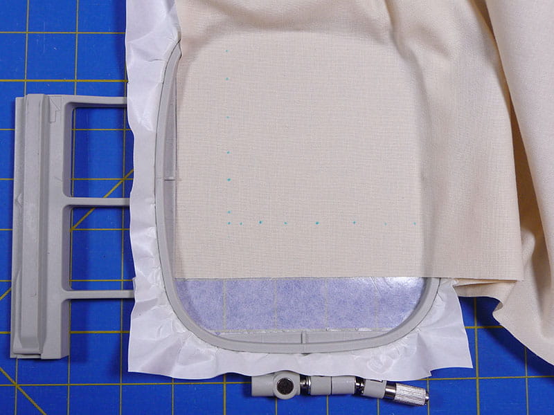 Embroidery hoop set up with cream fabric on a sewing board.