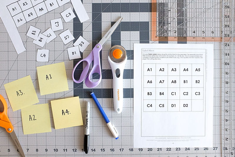 Square numbers and labeled sticky notes on a cutting board with pen, pencil and scissors