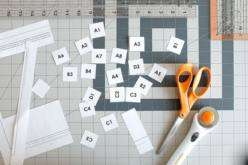 Cut out fabric labels on cutting board next to scissors and rotary cutter.