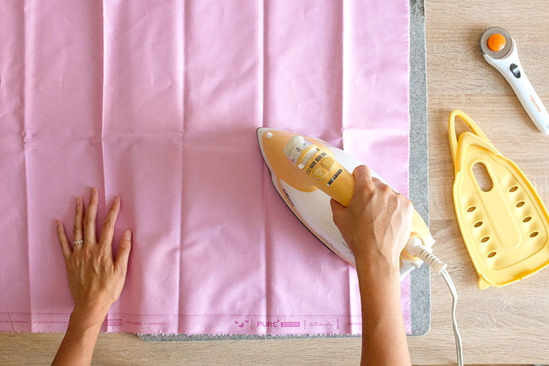 Person ironing pink fabric
