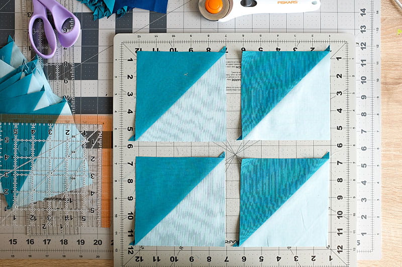 4 color block teal and light blue fabric squares on a table.