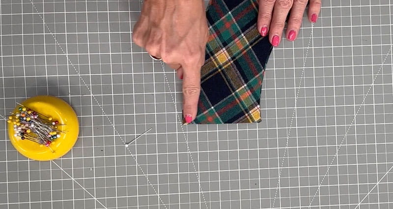 hand showing the end of the fabric pin holder with pins right next to it