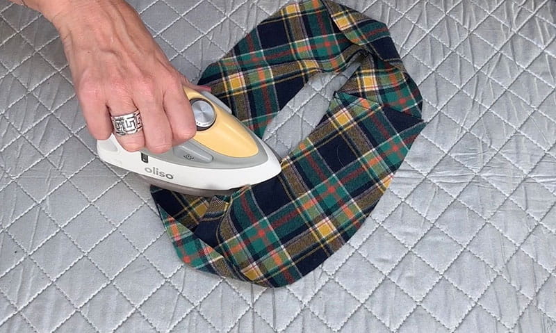 hand with iron pressing seam in white background