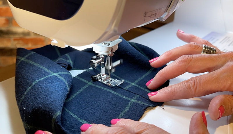 hand holding cloth while using sewing machine to sew it together