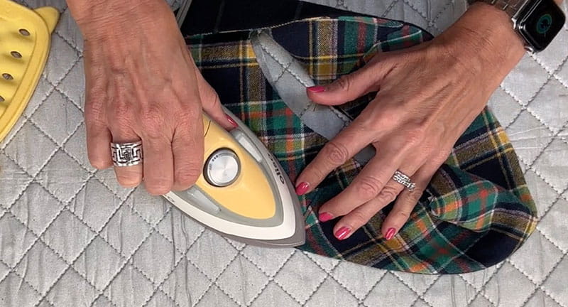 hands holding the cloth while ironing the right side of the brim