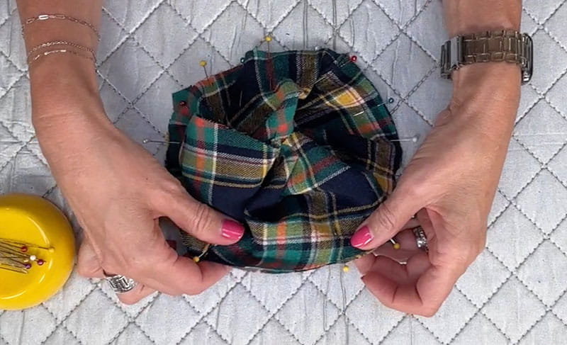 hands pinning cloth from a flannel shirt together white background