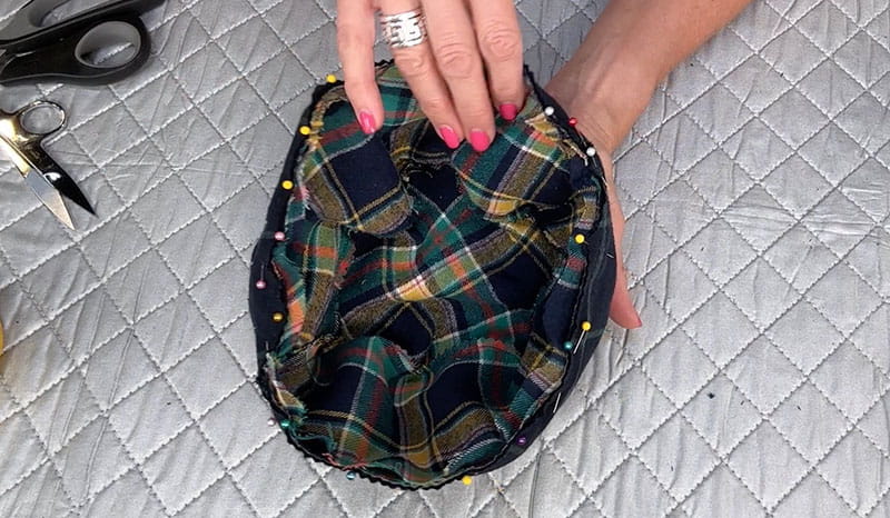 hands holding bucket hat using pins in the hat to hold the outer middle leaving opening