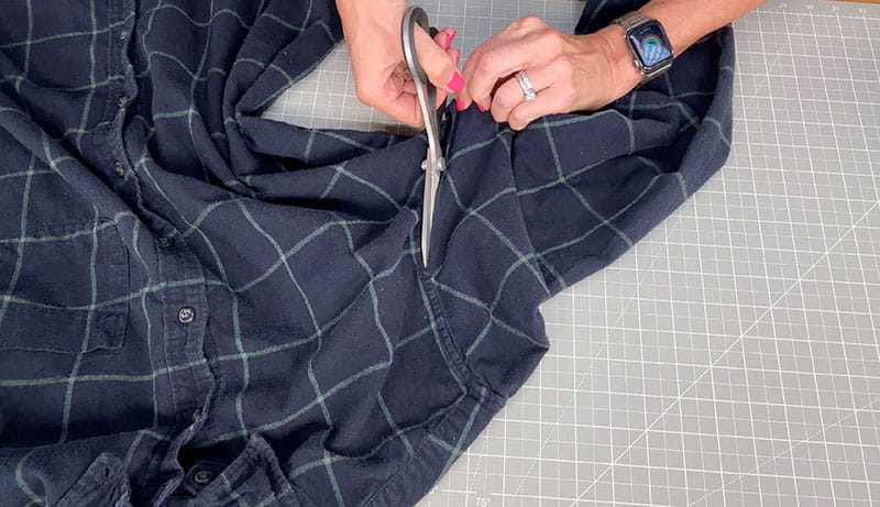 hand with scissors cutting the flannel shirt 