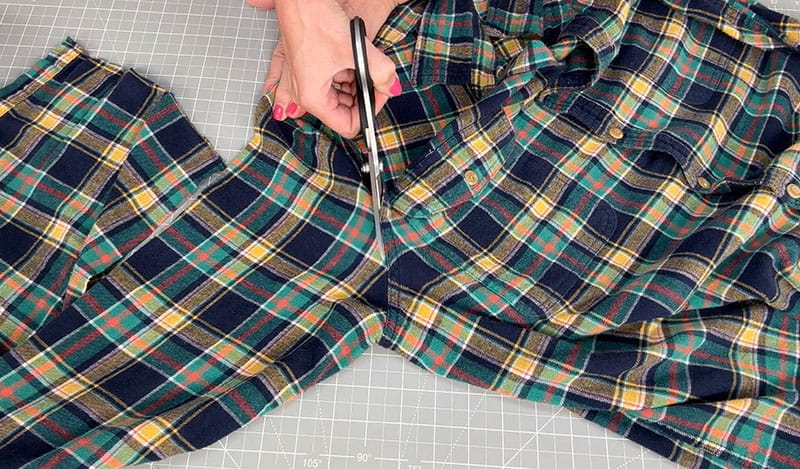 hand with scissors cutting the hands off the flannel shirt