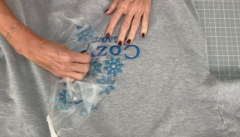 Finishing touches on grey sweatshirt with blue flowers