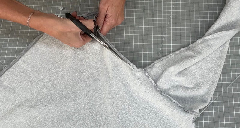 Grey sweatshirt getting side cut with scissors
