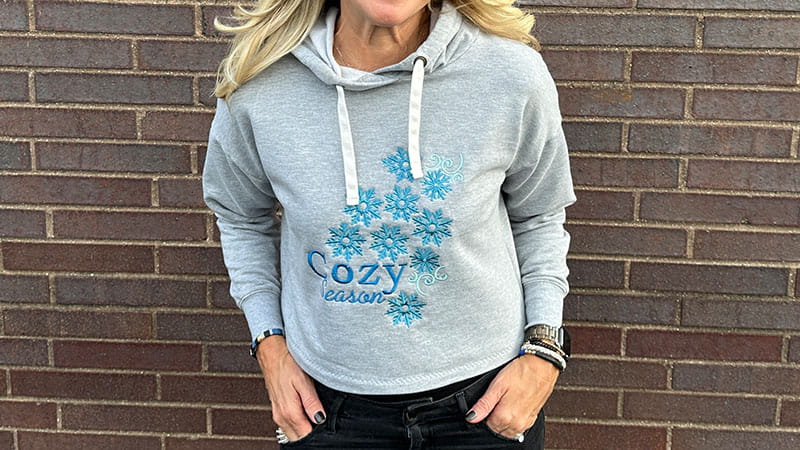 Grey sweatshirt with blue flower embroidery on woman