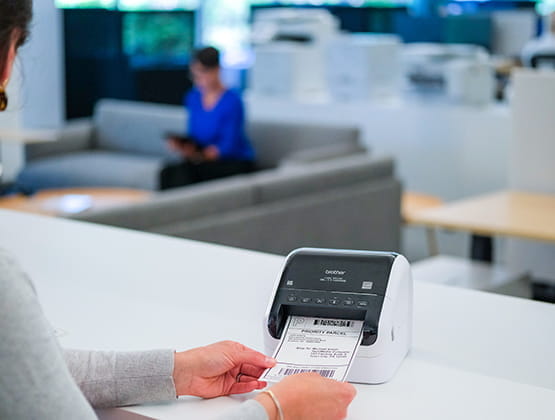 Person holding shipping labels printed on the QL-1110nwb label printer