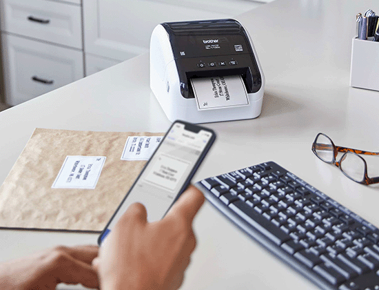 Person using a cell phone app to create shipping labels and printing on QL-1100C label printer. 