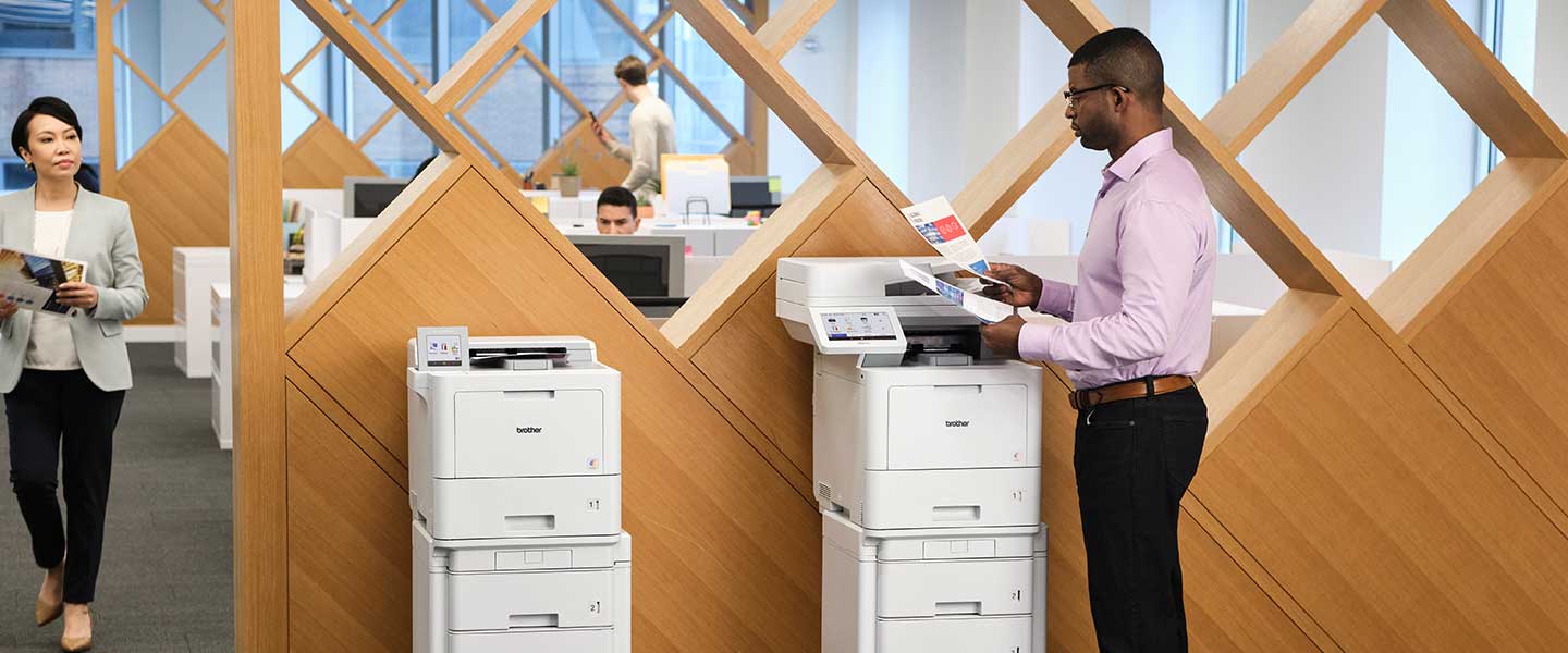 Man using Brother Workhorse series enterprise printer. Models shown HL-L9470 and MFC-L9670.