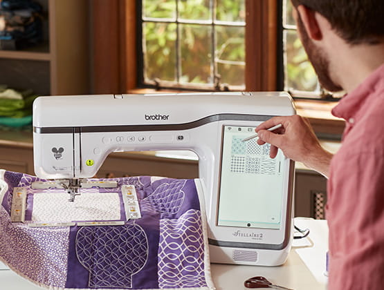 Man using LCD display on Stellaire2 embroidery machine to design quilt.