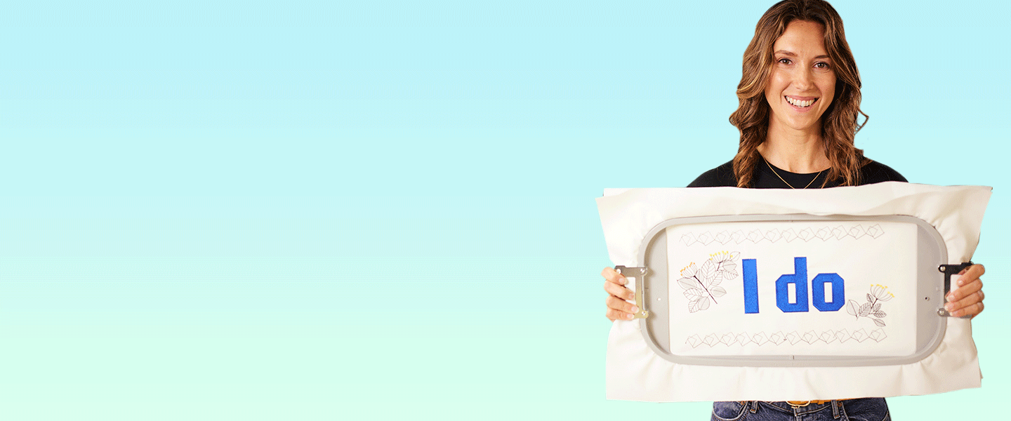 Woman holding an embroidery hoop with the words "I do" stitched into the fabric