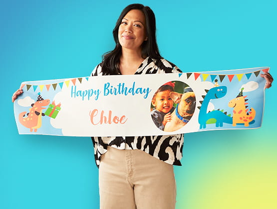Woman holding a sign reading "Happy Birthday Chloe" with dinosaurs