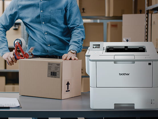 Box being taped shut by man with Brother printer in foreground