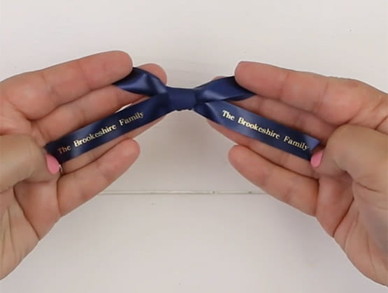 Hands tying Ptouch Embellish ribbon in a bow
