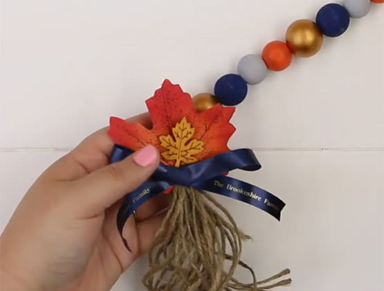 Person affixing Ptouch Embellish ribbon to tassel and garland string