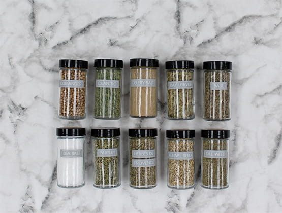 A variety of spices laying on marble countertop, with labels on them printed on Brother Ptouch 