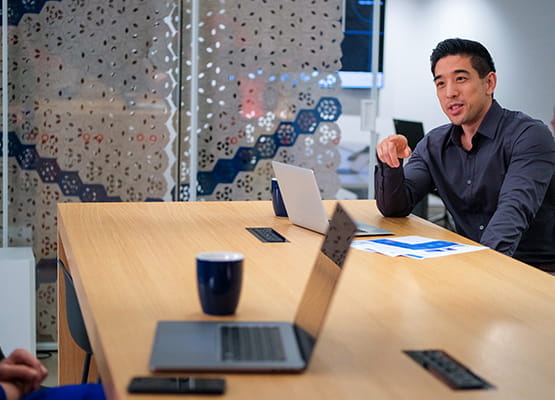 Man sitting in conference room with open laptop